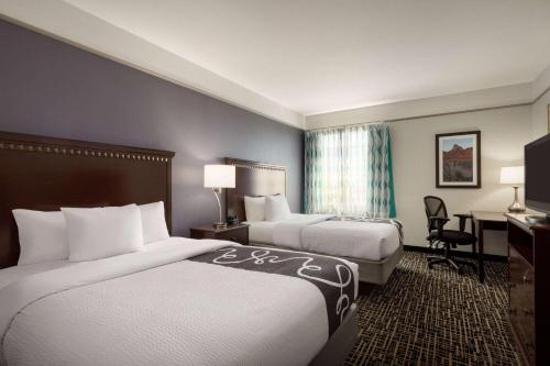 a hotel room with two beds and a desk at La Quinta by Wyndham Dumas in Dumas