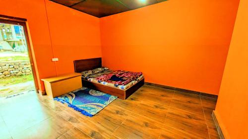 an orange room with a bed and a chair in it at Lamsang residency in Chug