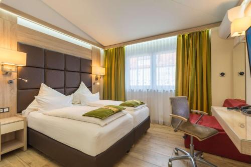 ein Hotelzimmer mit einem großen Bett und einem Schreibtisch in der Unterkunft Best Western Plus Hotel Füssen in Füssen