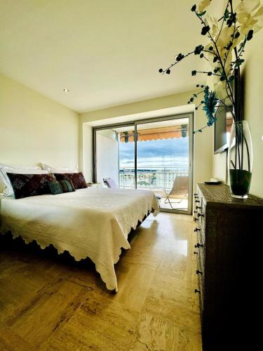 une chambre avec un grand lit et une grande fenêtre dans l'établissement Seaview Retreat 1BR with terrace, à Cannes