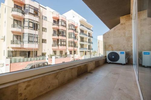 an apartment balcony with a large window with a view of a building at Clover Leaf Apartment B 03 by Homely Malta! in St. Paul's Bay