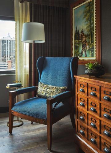 a blue chair in a room with a painting and a dresser at Graduate by Hilton Ann Arbor in Ann Arbor