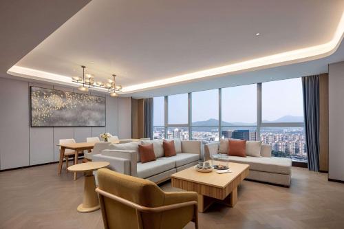a living room with a couch and tables and windows at Wyndham Hotel Guangzhou Huangbian Metro Branch - Free shuttle bus to Canton Fair in Guangzhou