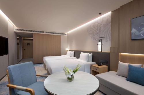 a hotel room with two beds and a table and a couch at Wyndham Hotel Guangzhou Huangbian Metro Branch - Free shuttle bus to Canton Fair in Guangzhou