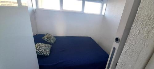 Cette petite chambre comprend un lit bleu avec deux oreillers. dans l'établissement Appartement 357, PORT NATURE colline 3 au village naturiste, au Cap d'Agde