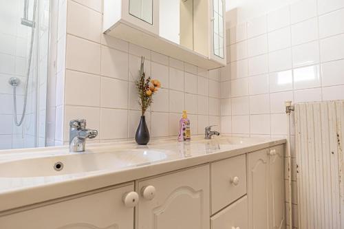 a bathroom with a sink and a vase of flowers at Cozy Central 11BR shared Stay with Garden Access & Terrace in Vienna