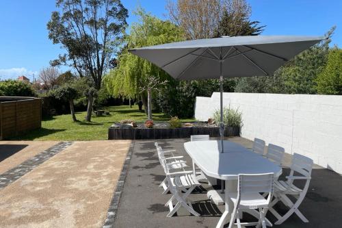 ein Tisch und Stühle mit einem Sonnenschirm auf einer Terrasse in der Unterkunft La Cabane Rouge - Wifi - Parking in Les Bussolleries