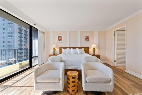 une chambre d'hôtel avec un lit et deux chaises dans l'établissement Aloha Seaside Vacations 4 Star Wyndham Resort 1803 Waikiki, à Honolulu