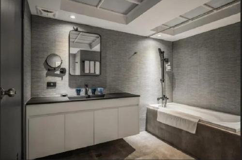 a bathroom with a tub and a sink and a mirror at CU Hotel Kaohsiung in Kaohsiung