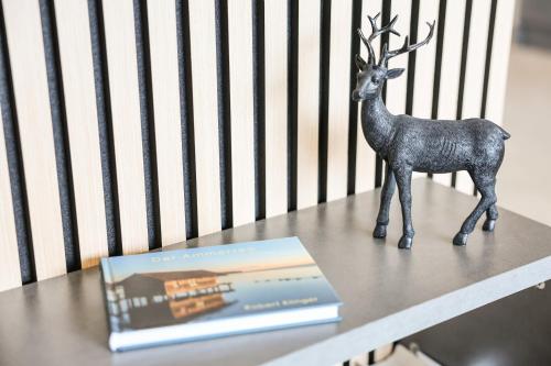 a statue of a deer standing on a table with a book at SEEZEIT Ferienwohnungen & Seminarhaus am Ammersee in Dießen am Ammersee