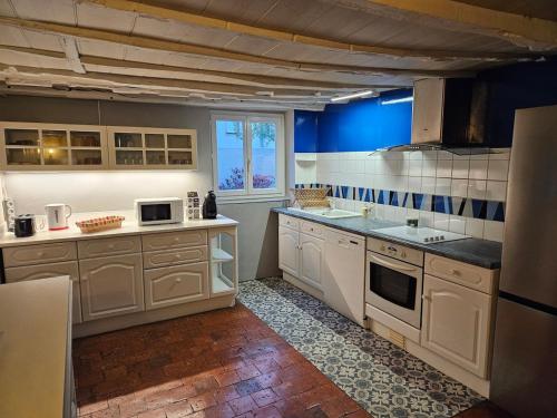 - une cuisine avec des appareils blancs et un mur bleu dans l'établissement La longère de Fabien, à Saint-Jean-de-Braye