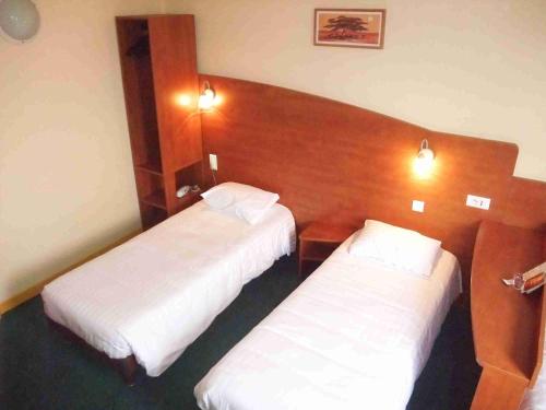two beds in a hotel room with white sheets at Adams Hotel in Metz