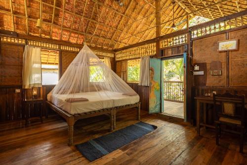 a bed in a room with a mosquito net at Bhakti Kutir in Palolem