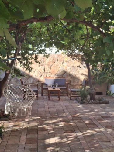 a patio with two benches and a table under a tree at Casa vacanze Siniscola in Siniscola