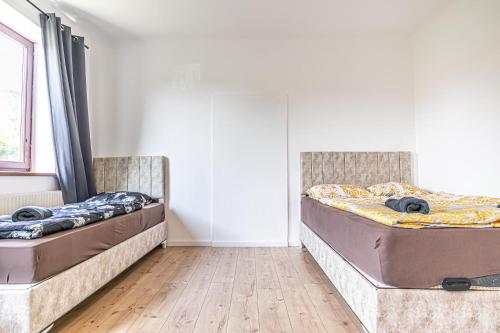two beds sitting in a room with wooden floors at Cozy Central 11BR shared Stay with Garden Access & Terrace in Vienna