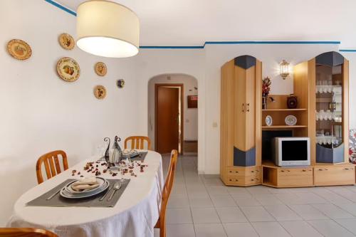 a dining room with a table and a tv at A sua casa no Algarve in Armação de Pêra