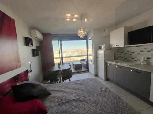 Cet appartement comprend une chambre avec un lit et une cuisine avec vue. dans l'établissement Studio 17C, HELIOPOLIS C au village naturiste, au Cap d'Agde