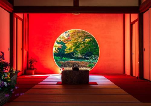 a room with a red wall with a round window at Villa Lotus in Kamakura