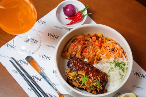 a bowl of food with rice and meat on a table at Wink Hotel Can Tho Ninh Kieu Wharf - 24hrs Stay & Rooftop Pool Bar in Can Tho