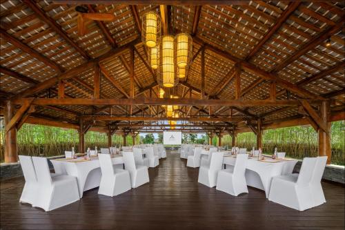 un largo salón de banquetes con mesas blancas y sillas blancas en Six Senses Qing Cheng Mountain, en Chengdú
