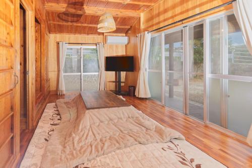 a bedroom with a large bed in a room with windows at たーちやー in Motobu