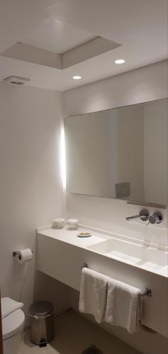 a bathroom with a mirror and a toilet with towels at Spetses Hotel in Spetses