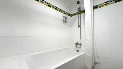 a white bath tub with a shower curtain in a bathroom at Pinnacle Lumpinee Park Hotel in Bangkok