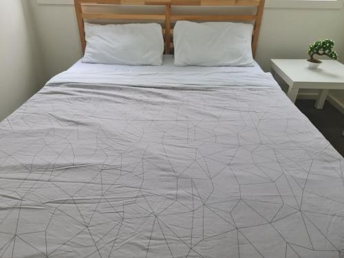 a bed with a gray comforter and white sheets at Serenity Home 11 by Hiverooms in Pakenham