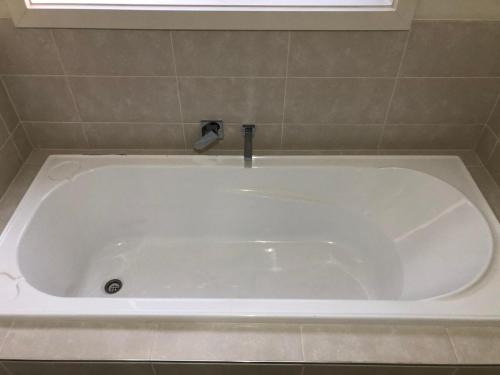 a white bath tub with a faucet in a bathroom at Serenity Home 11 by Hiverooms in Pakenham