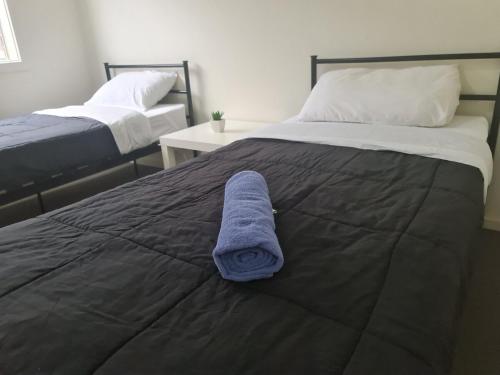 a bed with a blue towel sitting on top of it at Serenity Home 11 by Hiverooms in Pakenham