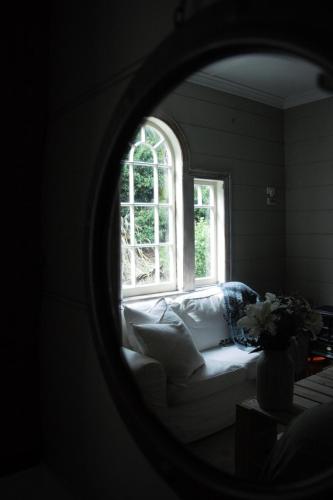 a living room with a white couch and a window at Freshwaterfarm Cottages - Muriwai in Waimauku