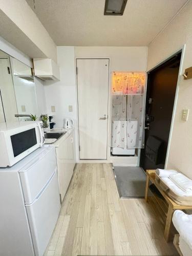 a small kitchen with a microwave and a refrigerator at ying-Shinjuku hostel-SJ0055 in Tokyo