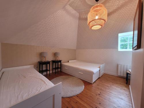 - une chambre avec un lit, deux tables et un lustre dans l'établissement Maison de Maitre du 19ème siècle- Honfleur, à Gonneville-sur-Honfleur