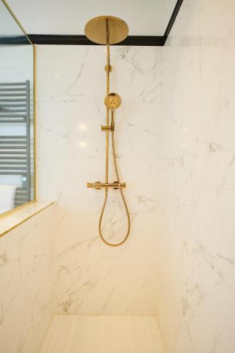 a shower in a bathroom with white marble walls at Les Bains de Spa in Spa
