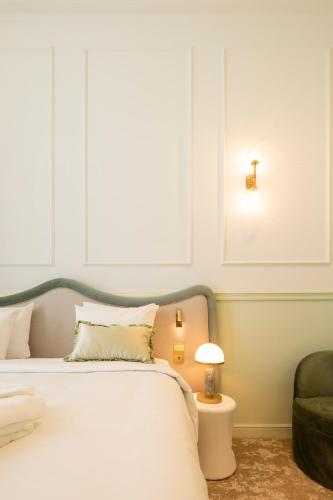 a bedroom with a white bed and a green chair at Les Bains de Spa in Spa
