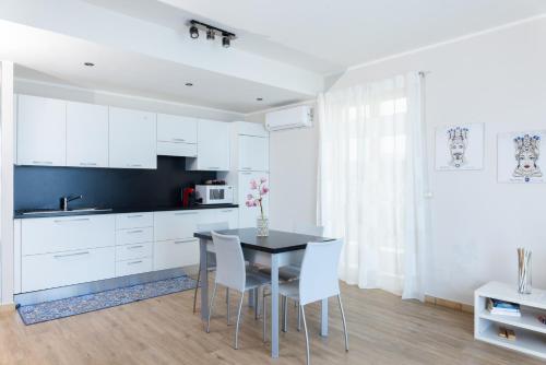 a kitchen with white cabinets and a table and chairs at Villa Da Vinci Luxury Panoramic Apartments - Taormina rooms collection in Taormina
