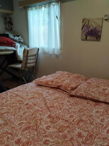 a bedroom with a bed and a chair and a window at Mobil home Var in Méounes-lès-Montrieux