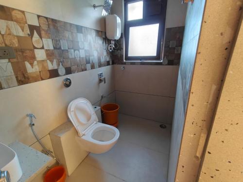 a bathroom with a white toilet and a window at Parin Hotel And Resort in Ratnagiri