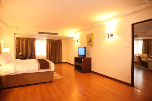 a hotel room with a bed and a flat screen tv at Furama Chiang Mai in Chiang Mai