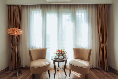 a living room with two chairs and a table with flowers at Thang Long Opera Hotel in Hanoi