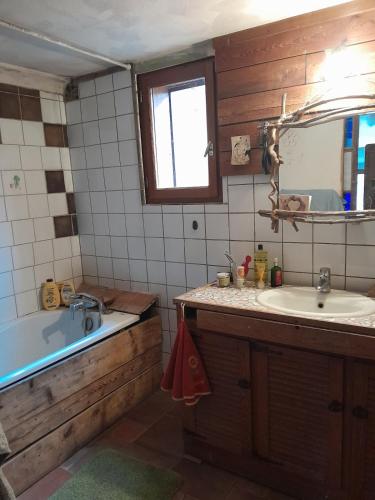 une salle de bain avec une baignoire, un lavabo et un miroir dans l'établissement Maison isolée tout équipée, à La Piarre