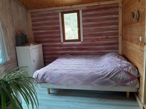 Ce lit se trouve dans une chambre en bois dotée d'une fenêtre. dans l'établissement Maison isolée tout équipée, à La Piarre