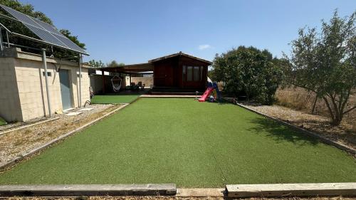 a yard with a green lawn with a house at Casa de Madera in El Palmar