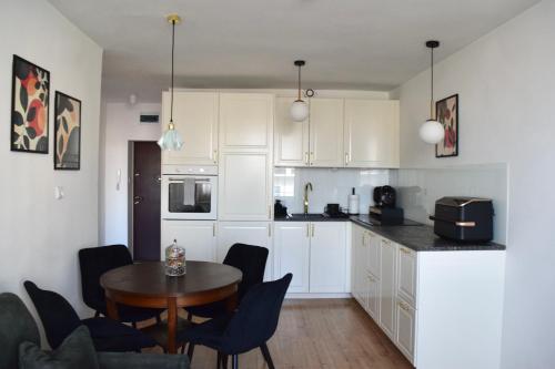 a kitchen with white cabinets and a table and chairs at Apartament Teatralny - Komfort w Sercu Miasta Klimatyzacja in Opole