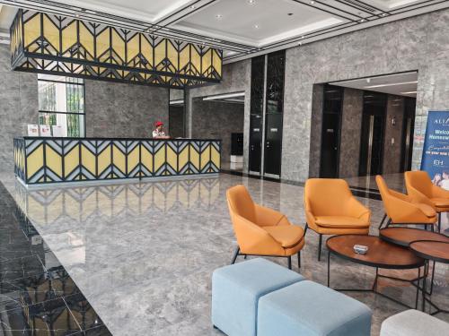 a lobby with orange chairs and a bar at Alinea Suites Shah Alam in Shah Alam
