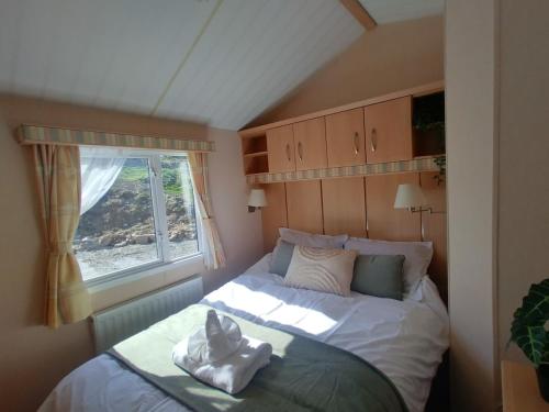 a small bedroom with a bed with a window at Seaside chalet in Ardmore with breathtaking views in Ardmore