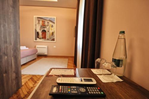 a table with remote controls and a bottle on it at Vila Casablanca - Boutique Hotel & Restaurant in Shkodër