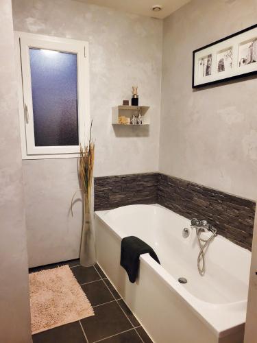 La salle de bains est pourvue d'une baignoire blanche et d'une fenêtre. dans l'établissement Maison cosy entre mer et Brière, à Trignac