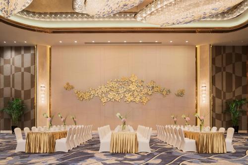 a banquet hall with white chairs and tables and flowers at Wanda Realm Changzhou in Changzhou