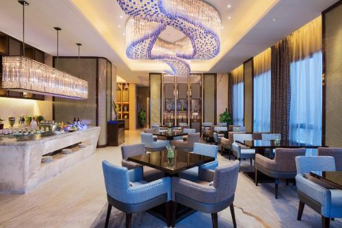 a restaurant with blue chairs and a chandelier at Wanda Realm Changzhou in Changzhou